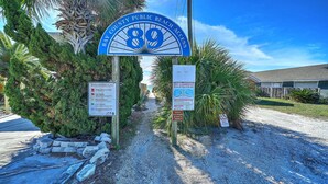 Señal de acceso a la playa para la Playa Pública del Condado, con avisos sobre corrientes de resaca y prohibición de mascotas.