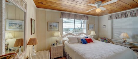 Ein Schlafzimmer mit einem großen Bett, einem Deckenventilator und einem Fenster mit Jalousien.