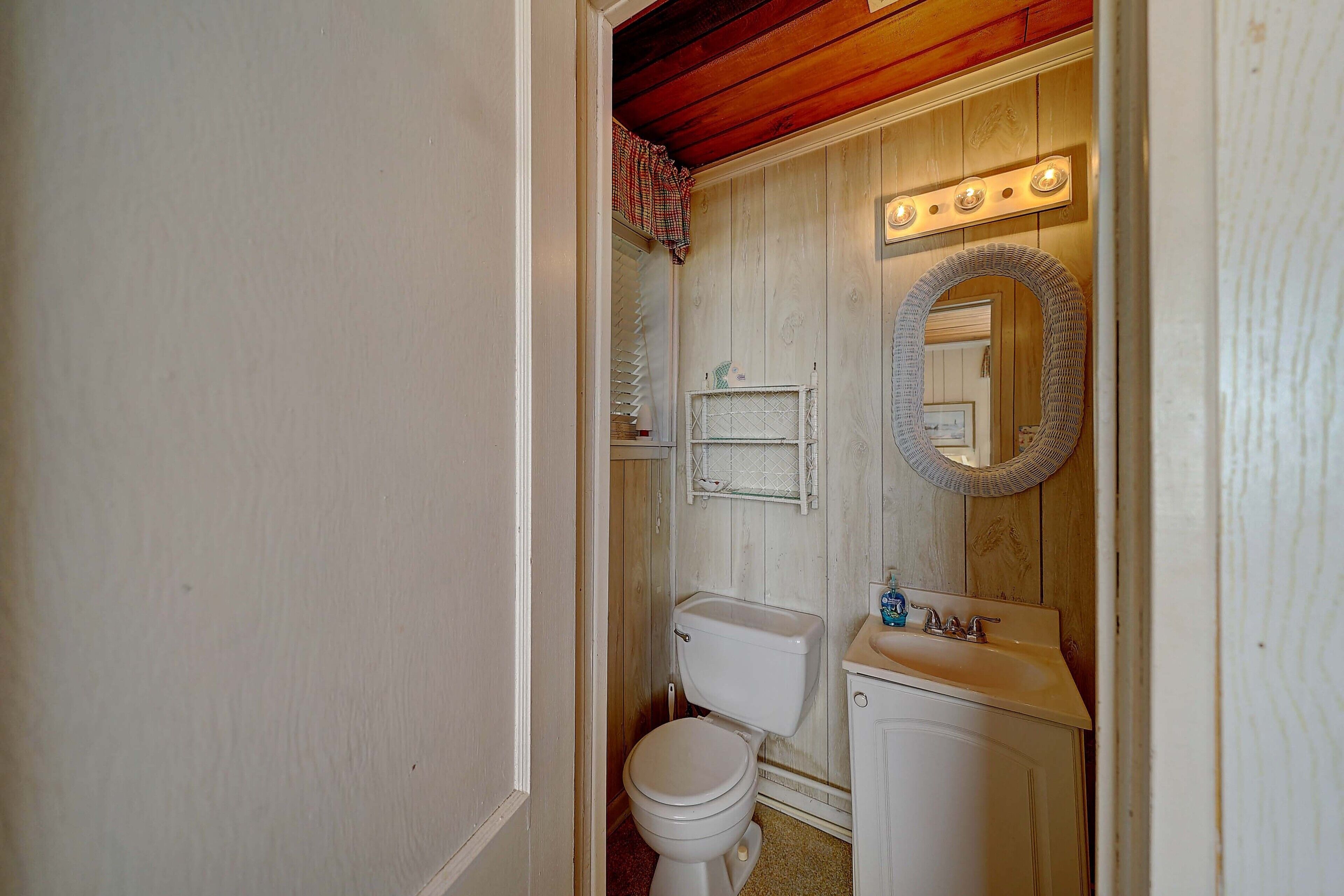 A bathroom with a toilet, sink, and mirror.