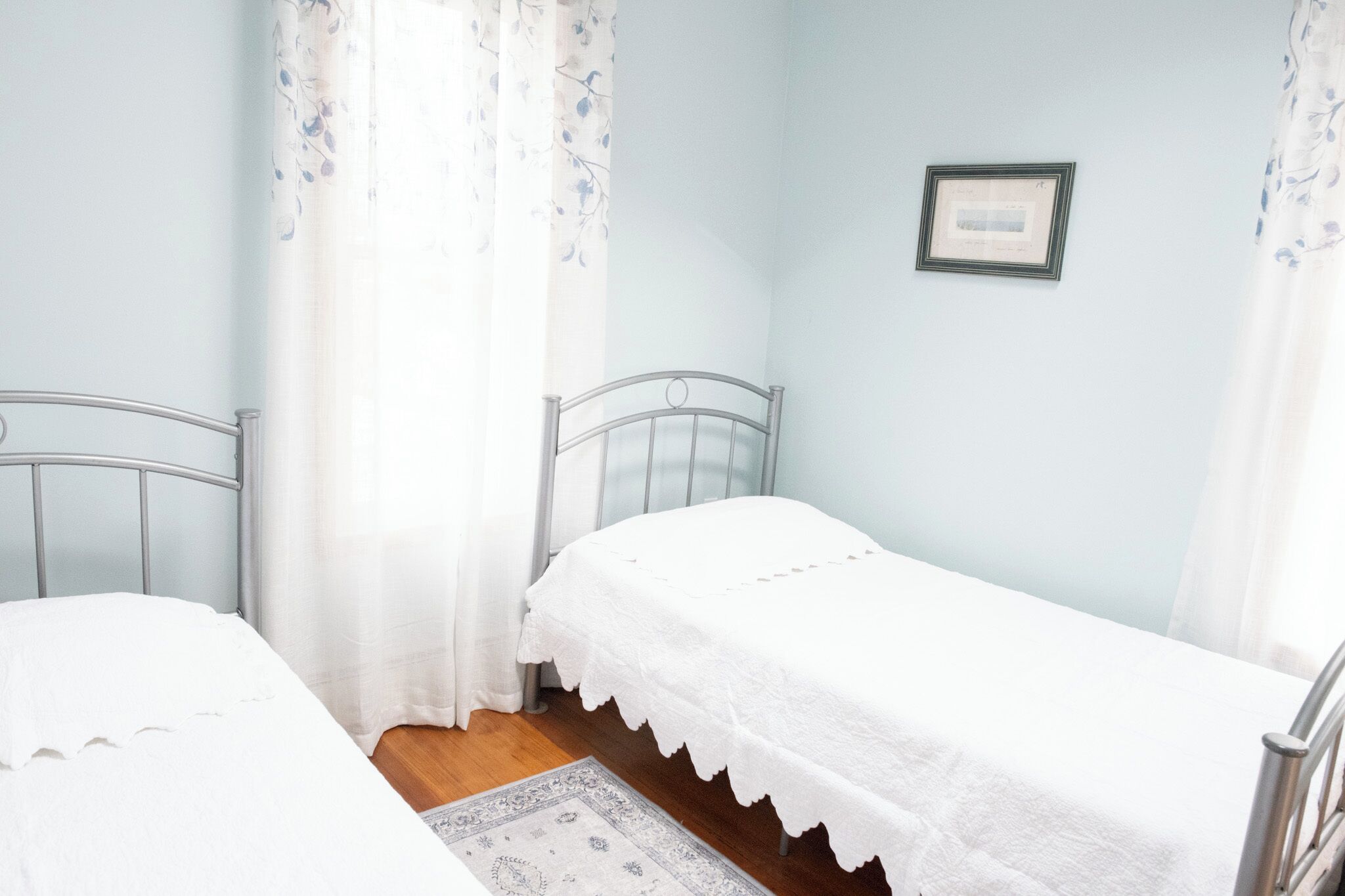 Ein Schlafzimmer mit zwei Einzelbetten, einem kleinen Teppich und einem gerahmten Zertifikat an der Wand.