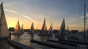 A marina with multiple sailboats docked at sunset.