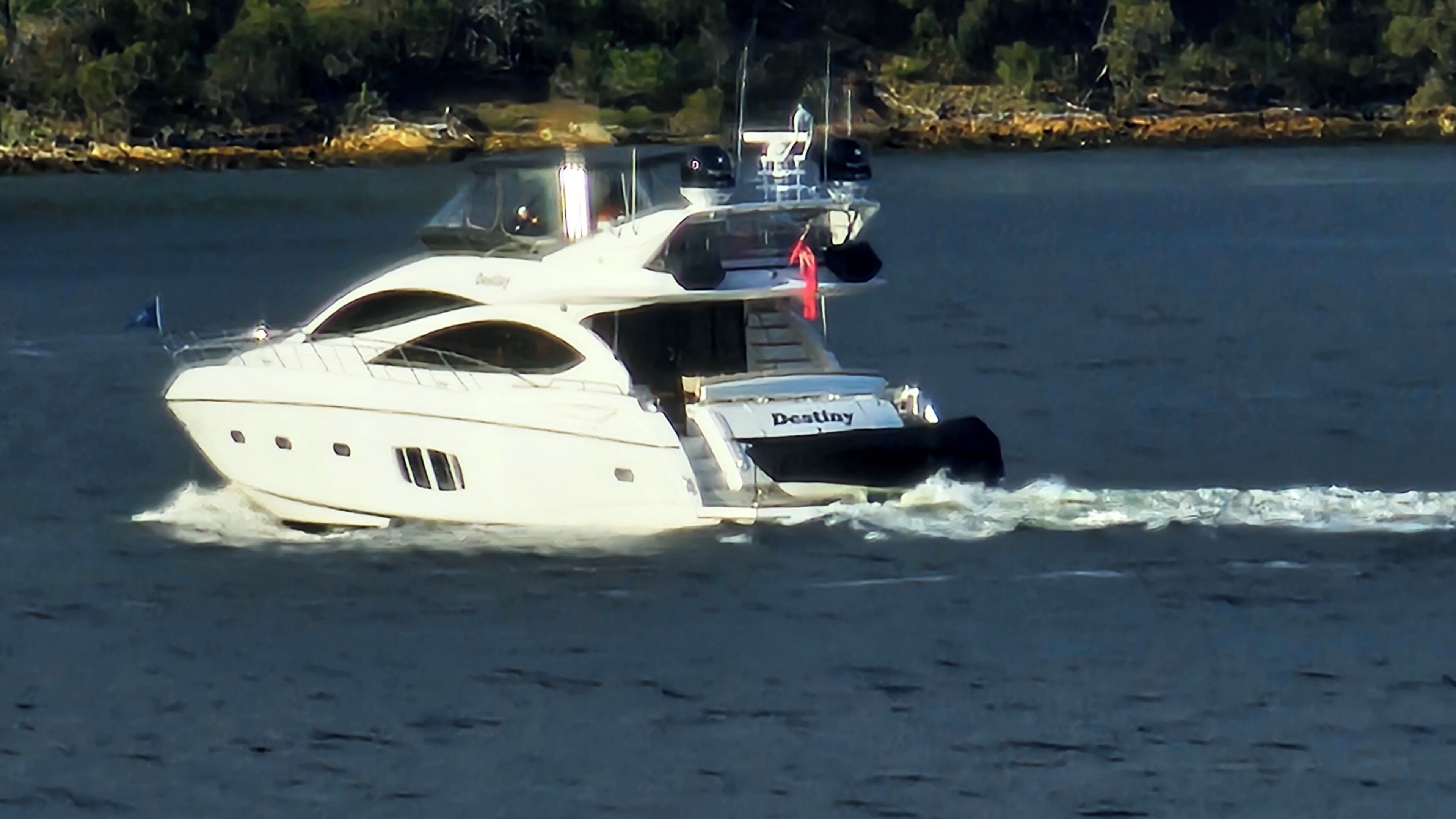 A luxury yacht with a name on the side, moving on calm water.