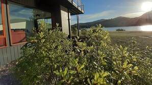 Ein modernes Gebäude mit einem Balkon mit Blick auf einen See und Berge.