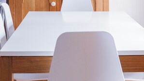 A room with a white table, a wooden cabinet, and a white chair.
