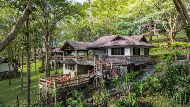 A two-story house with a stone facade, wooden deck, and a stone staircase leading to the upper level. - Khao Kho Valley Hotel (Khao Kho)