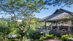 A traditional house with a stone base and a tiled roof, surrounded by lush greenery and trees. - Khao Kho Valley Hotel (Khao Kho)