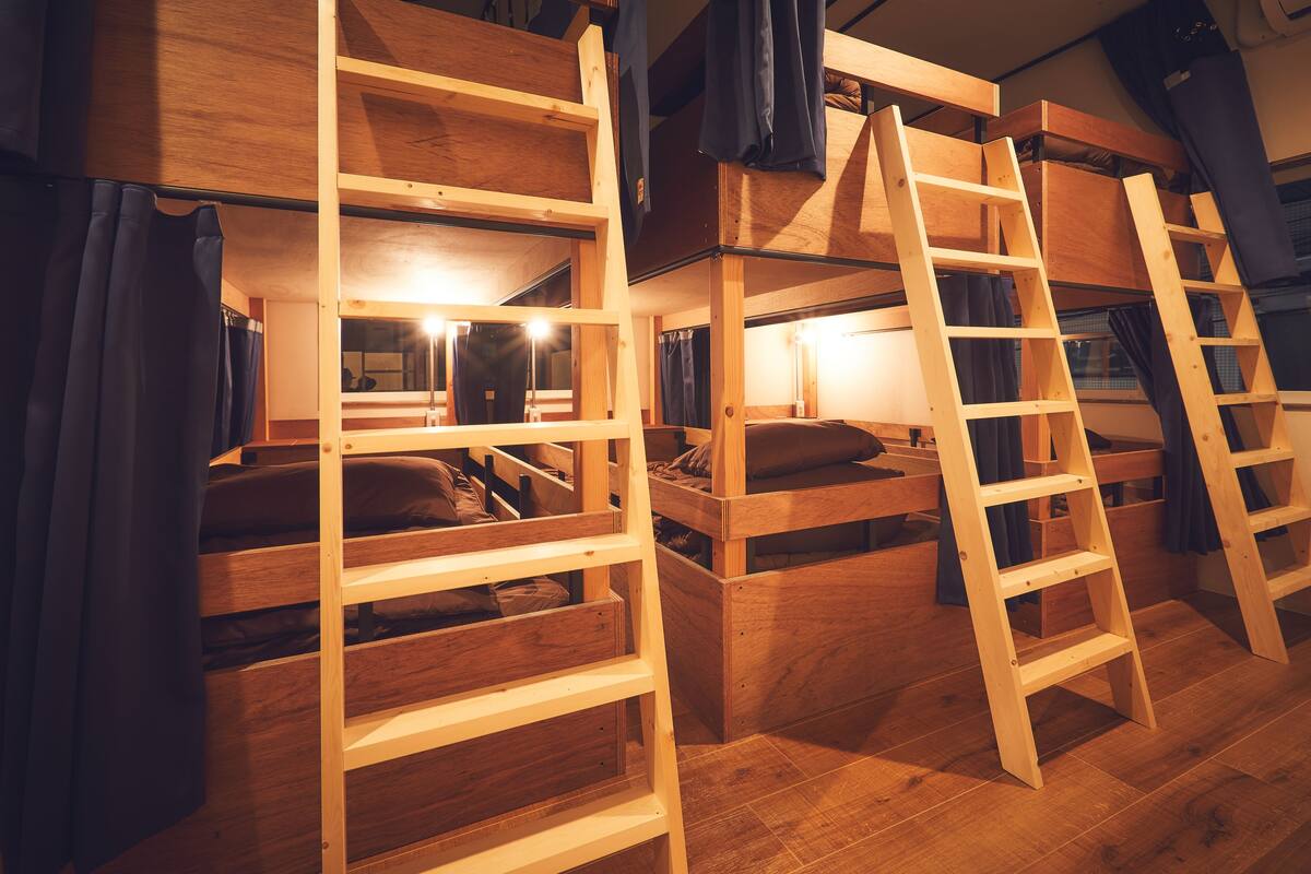 Camas literas de madera con escaleras, una ventana y una cortina.
