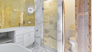 Une salle de bain avec un meuble-lavabo blanc, une douche à parois de verre et une porte en bois.