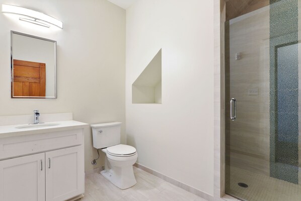 Een moderne badkamer met een witte wastafel, een toilet en een douchecabine van glas.