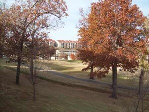A building with a red roof and a grassy area in front. - Walk-In Shower /New Decor/ Kings/ CLEAN/ Indoor-Outdoor Pools/ Golf View on 10th (Branson)