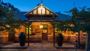 A building with a brick facade, a wooden entrance canopy, and large vases at the entrance. - Rent your own Hotel in the Victorian Goldfields (Maldon)