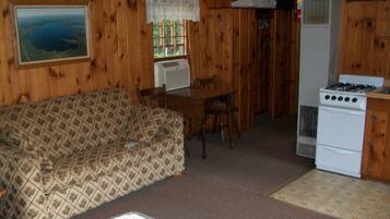 A cozy cabin interior with a wooden interior, a sofa, a dining table, and a kitchenette area.