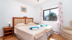 A bedroom with a double bed, a nightstand, a chair, and a window with curtains. - Casa Prensa - Private pool, 5 minute drive to Carvoeiro & beach (Lagoa)