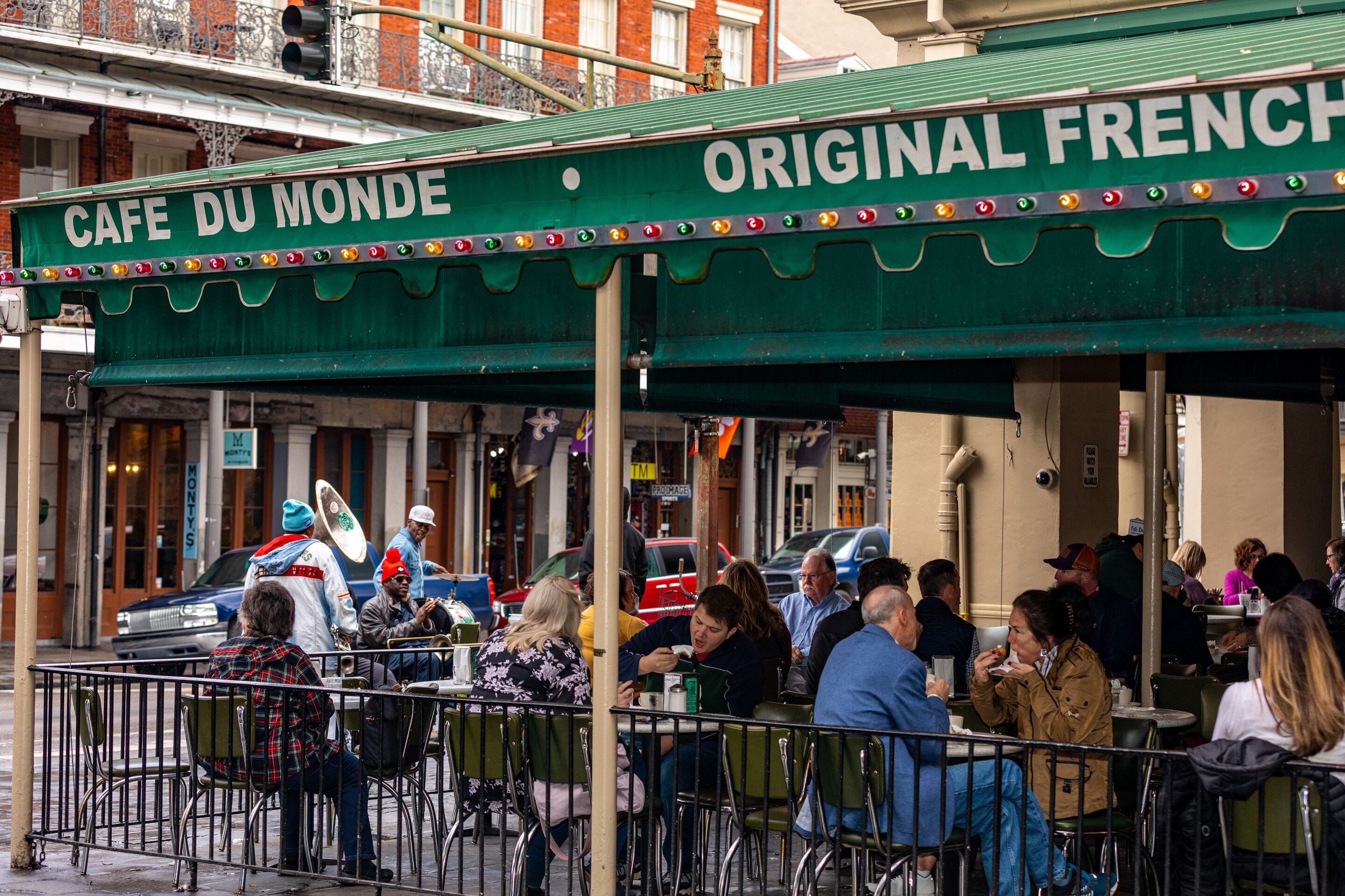 Un café con mesas al aire libre y un toldo verde que dice "Cafe Du Monde".