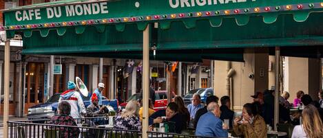 Un café con mesas al aire libre y un toldo verde que dice "Cafe Du Monde".
