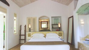 Une chambre spacieuse avec un grand lit, un ventilateur de plafond et un tapis à motifs.