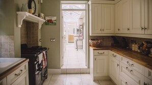 Una cocina con armarios blancos, una estufa y un salpicadero de azulejos.
