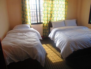 A room with two single beds, a window with a view, and a radiator.