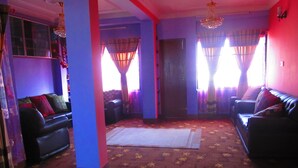 A living room with two sofas, a patterned carpet, and a chandelier. - Sunrise Homestay Nepal (Tohka)