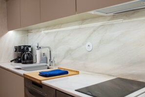 Cozinha moderna com bancada de mármore, cafeteira, pia e um tablet.