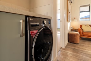 A compact washer and dryer unit with a direct drive motor, a control panel with various settings, and a red sticker indicating its features. - Twizel Cottages (Twizel)