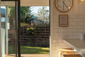 A kitchen with a wooden countertop, a wall-mounted clock, and a framed welcome sign. - Twizel Cottages (Twizel)