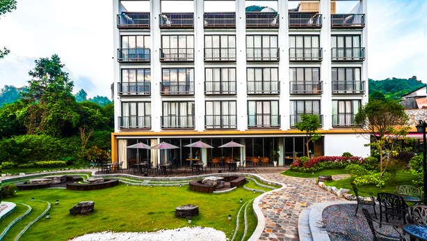 A modern hotel with multiple balconies, outdoor seating, and a landscaped garden. - Courtyard Hotel – Li River Branch (Guilin)
