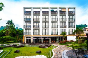 Een modern hotel met meerdere balkons, buiten zitplaatsen en een aangelegde tuin.