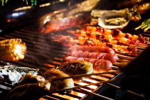 Una barbacoa amb diferents carns i marisc en preparació.