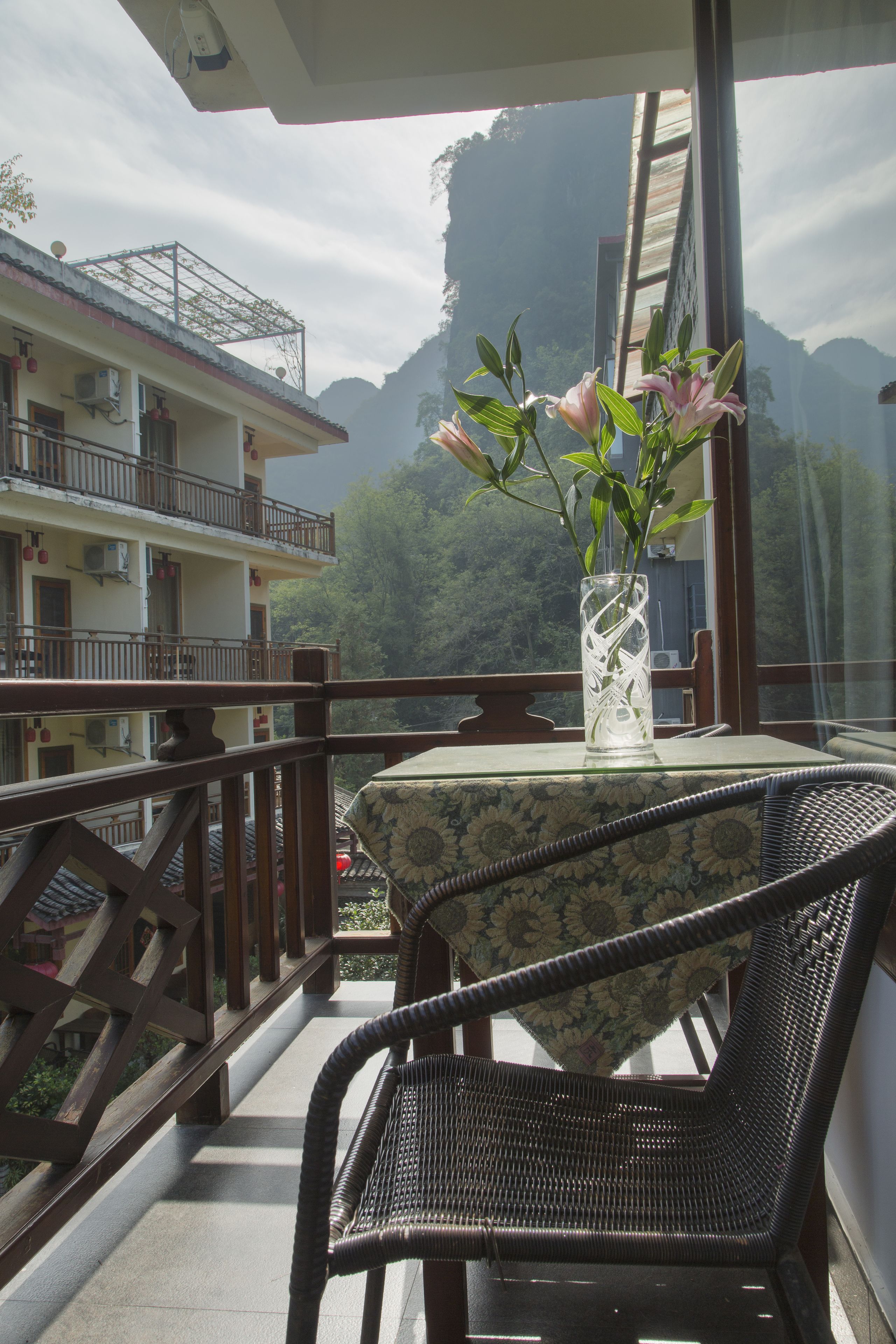 A balcony with a table and chairs, overlooking a mountainous landscape.