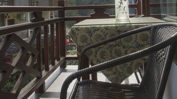 A balcony with a table and chairs, overlooking a mountainous landscape.