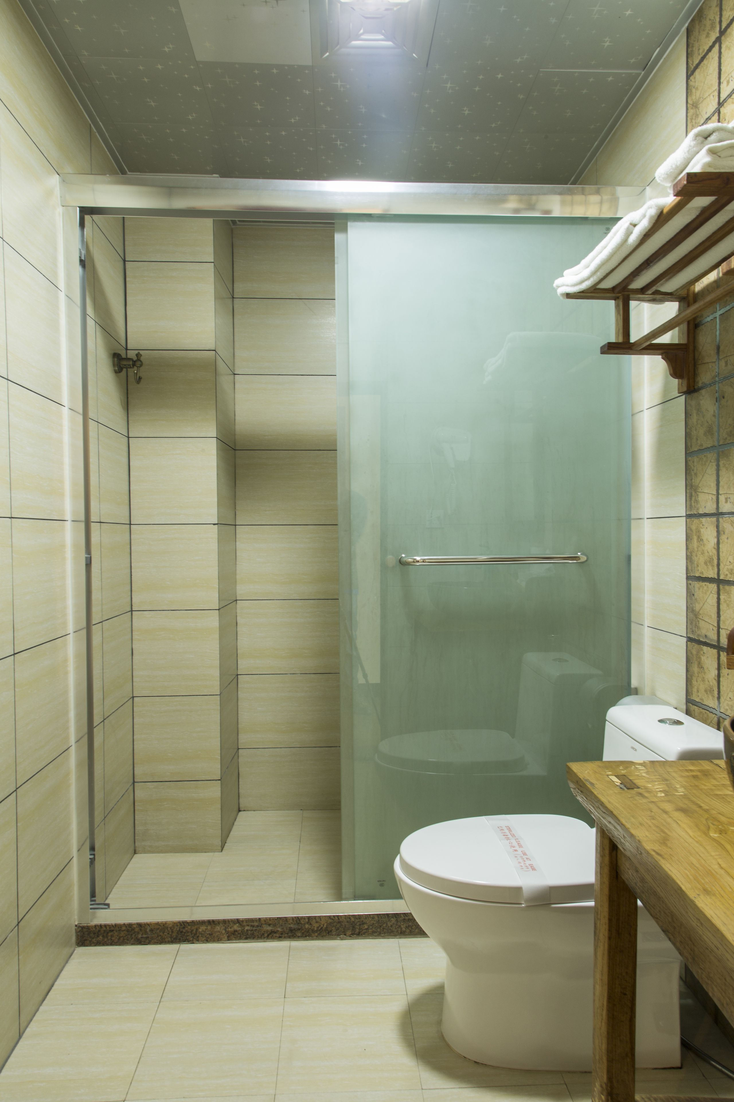 Un bany amb una cabina de dutxa de vidre, un vàter i un moble de bany de fusta.