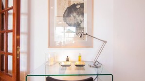 A glass desk with a framed artwork, a desk lamp, and a candle holder.