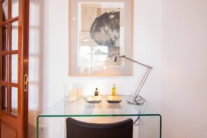 Ein Glastisch mit gerahmtem Kunstwerk, einer Schreibtischlampe und einem Kerzenhalter.
