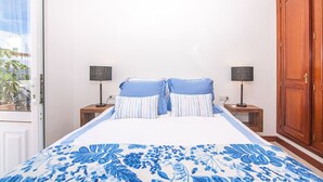 A bedroom with a bed, two bedside tables, a nightstand, and a wardrobe.