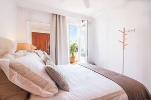 A bedroom with a bed, a window, a coat rack, and a view of the outdoors.