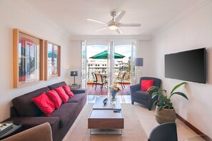 A modern living room with a sofa, armchair, coffee table, and a flat-screen TV.