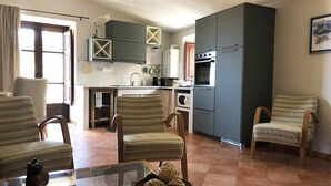 Uma cozinha moderna com armários escuros, uma ilha central e uma área de refeições com cadeiras listradas.