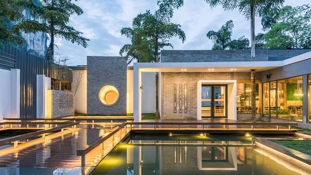 A modern building with a reflective pool, a circular light feature, and a brick wall with vertical slats. - Moon Villa Resort (Guilin)