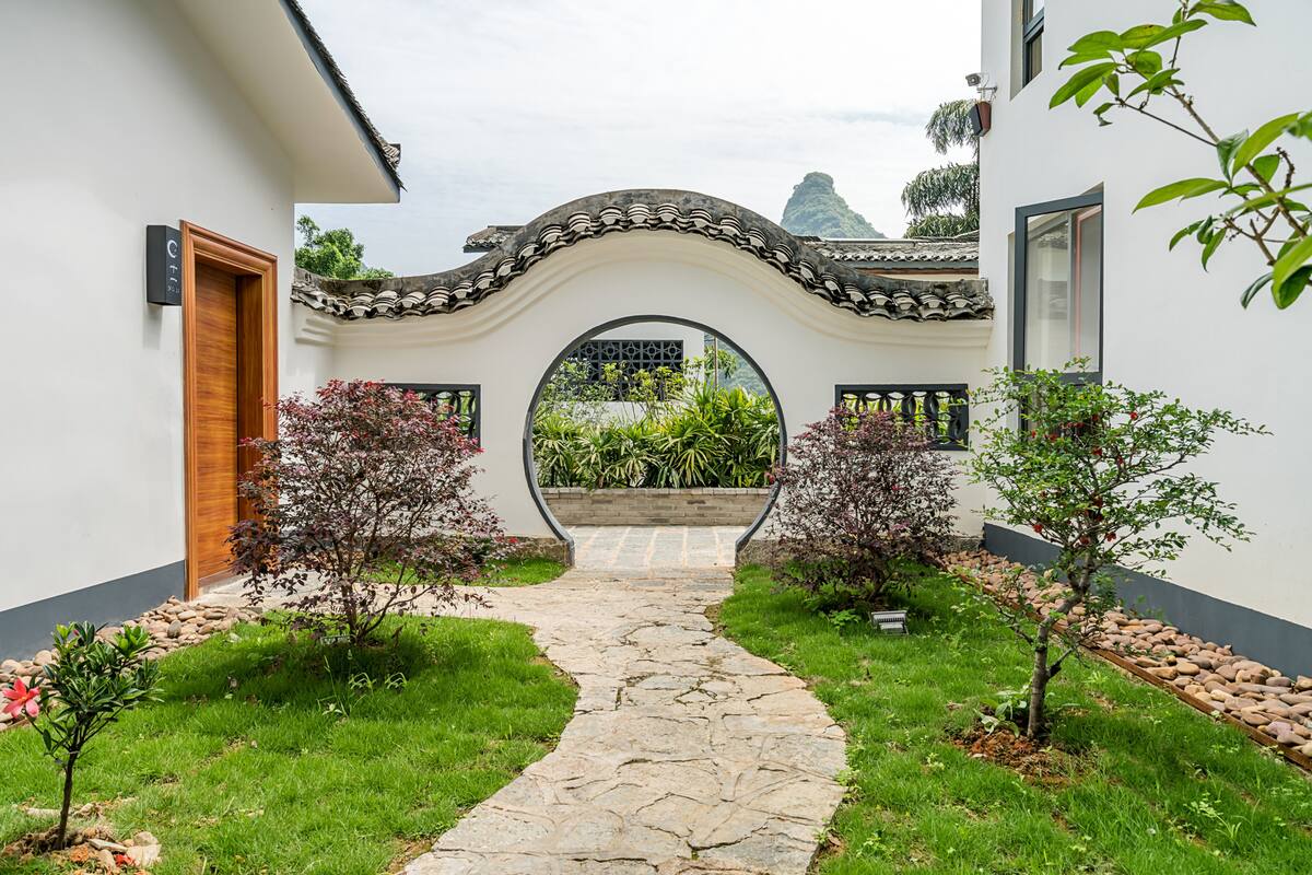 A pathway leading to a traditional archway with a garden on either side.