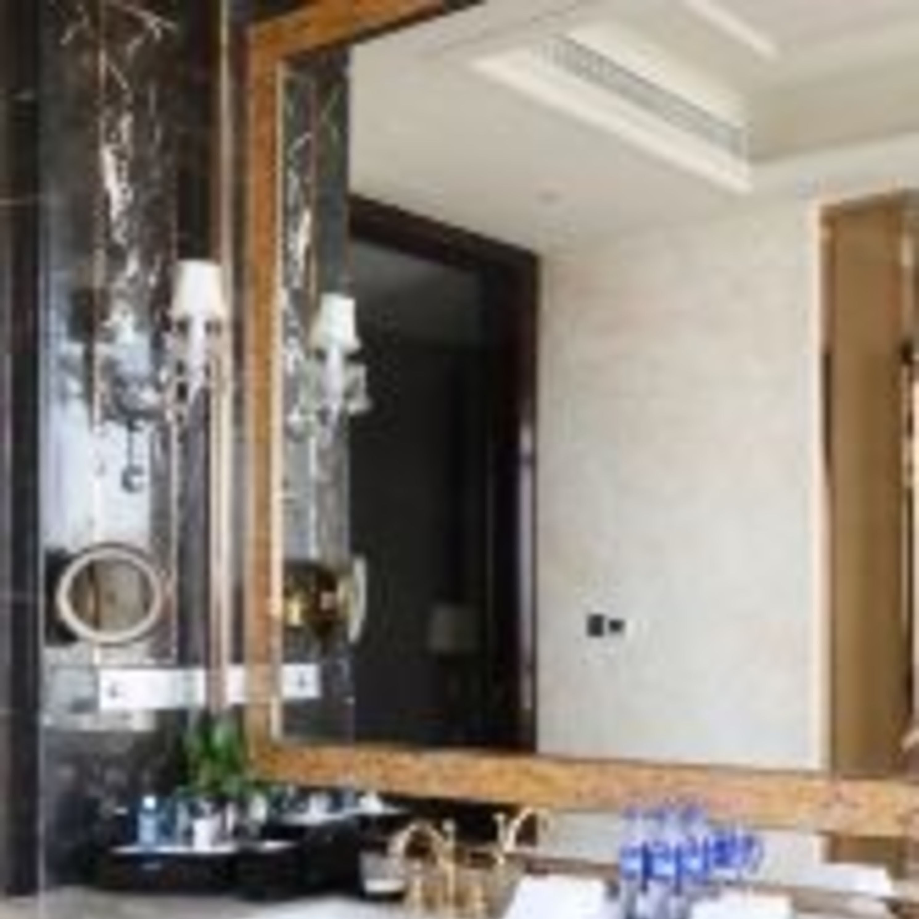 A modern bathroom with a large mirror, a round sink, and a dark marble wall.