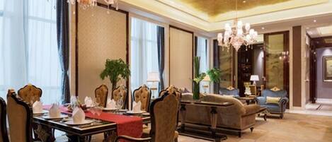 A luxurious hotel lobby with a dining area, elegant chandeliers, plush seating, and large windows.