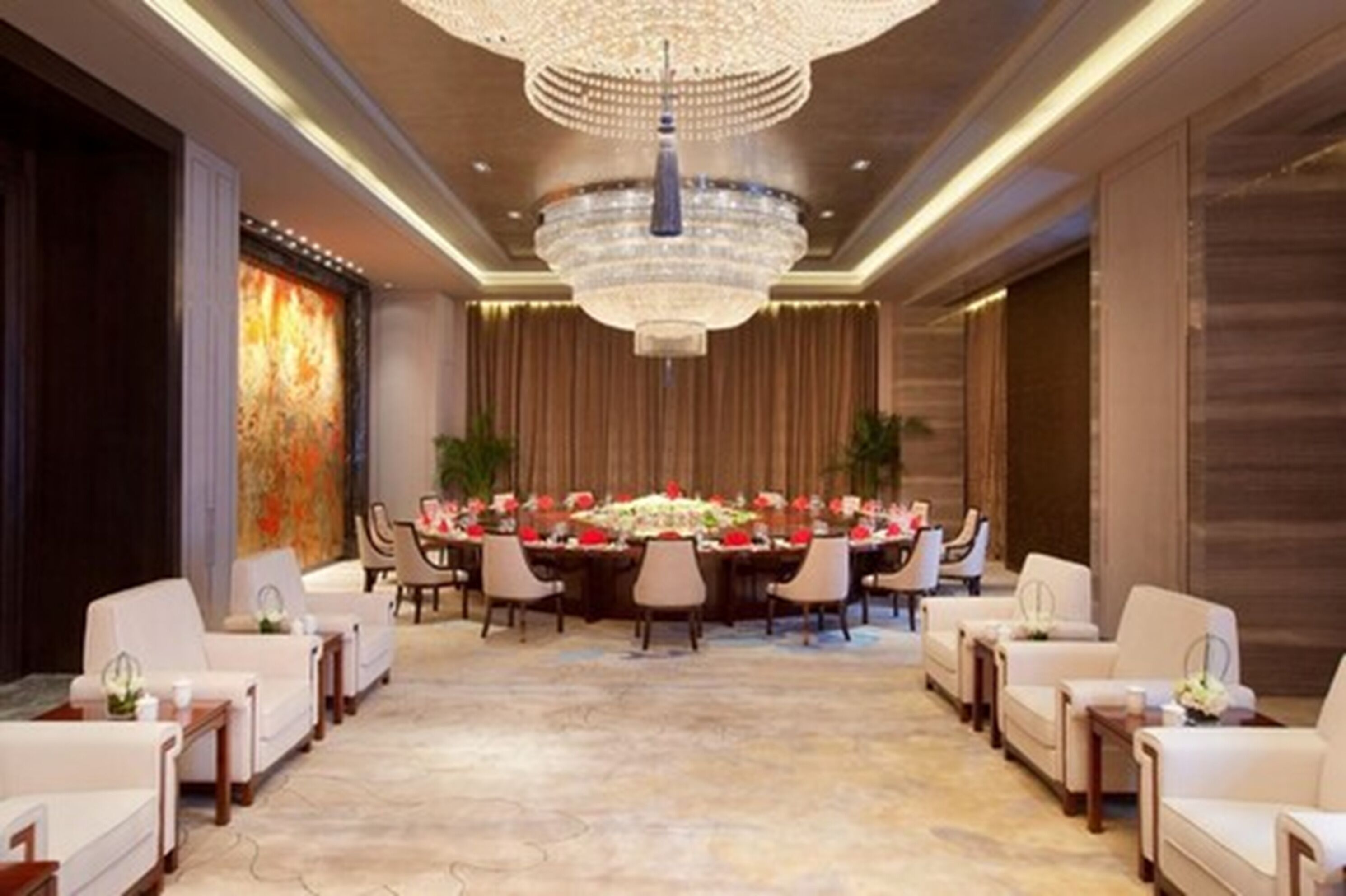 A spacious, elegantly decorated dining area with a large chandelier, a long table set for a meal, and comfortable seating on either side.