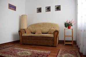 Un salon avec un canapé, une lampe, une petite table sur laquelle est posée une plante en pot et un tapis.