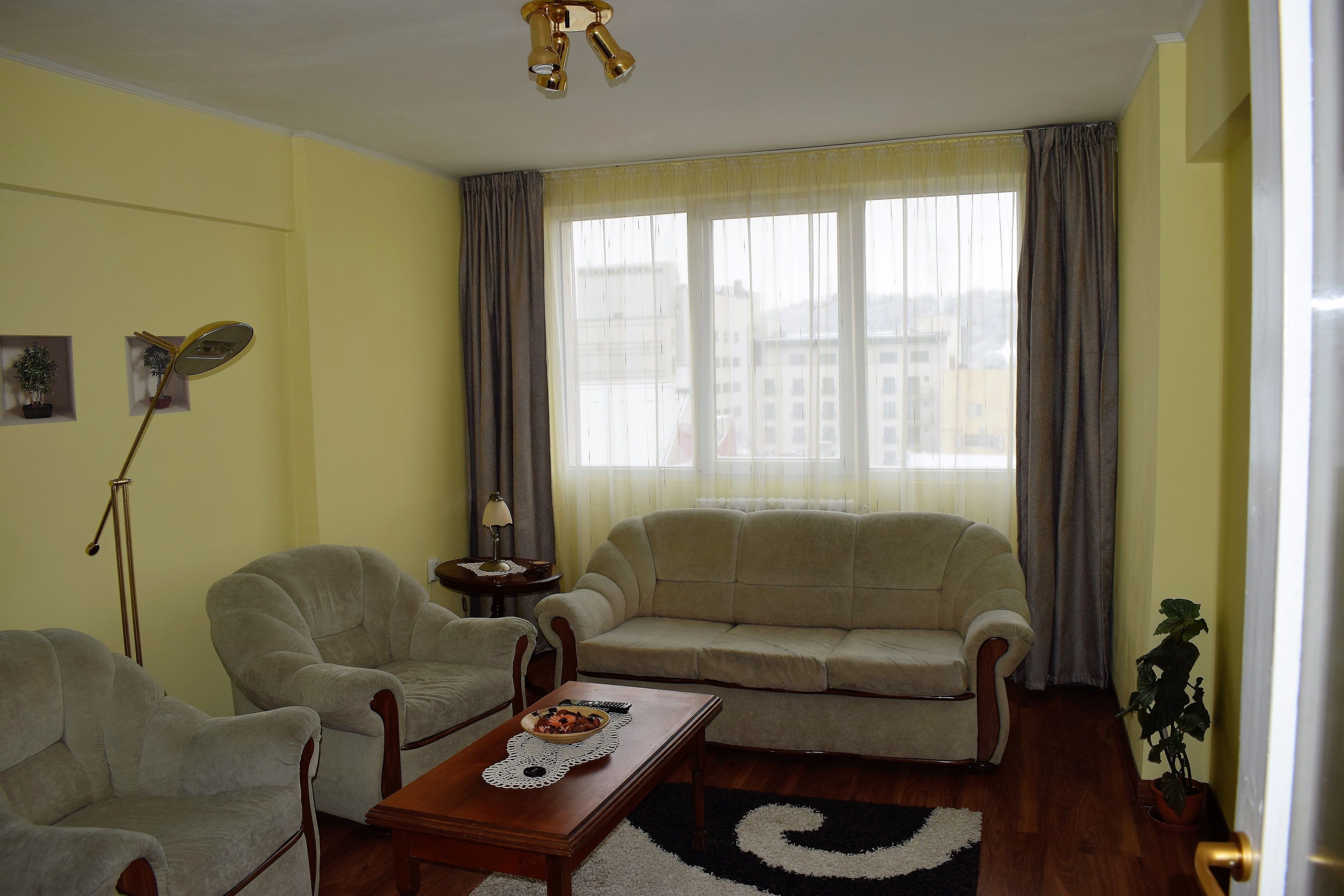 Una sala de estar con un sofá, dos sillones, una mesita de centro y una lámpara de pie.