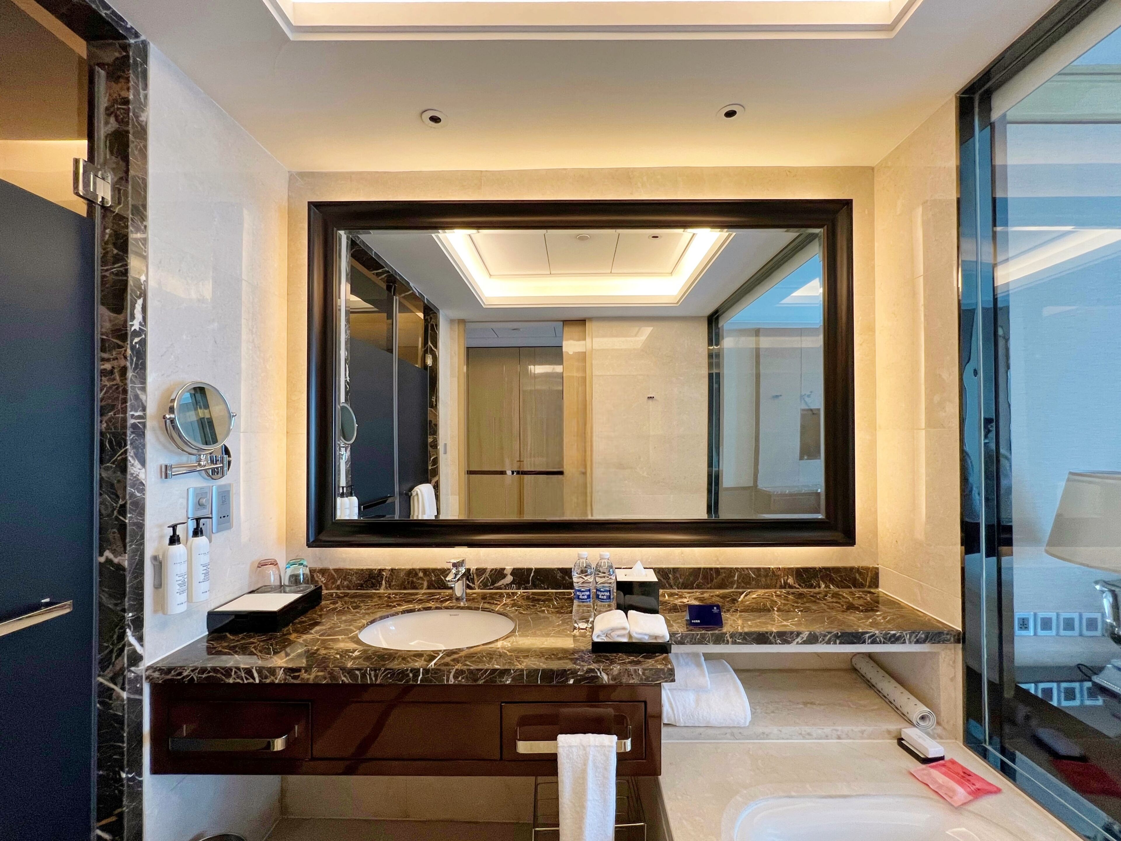 A modern bathroom with a large mirror, two sinks, and a glass shower enclosure.