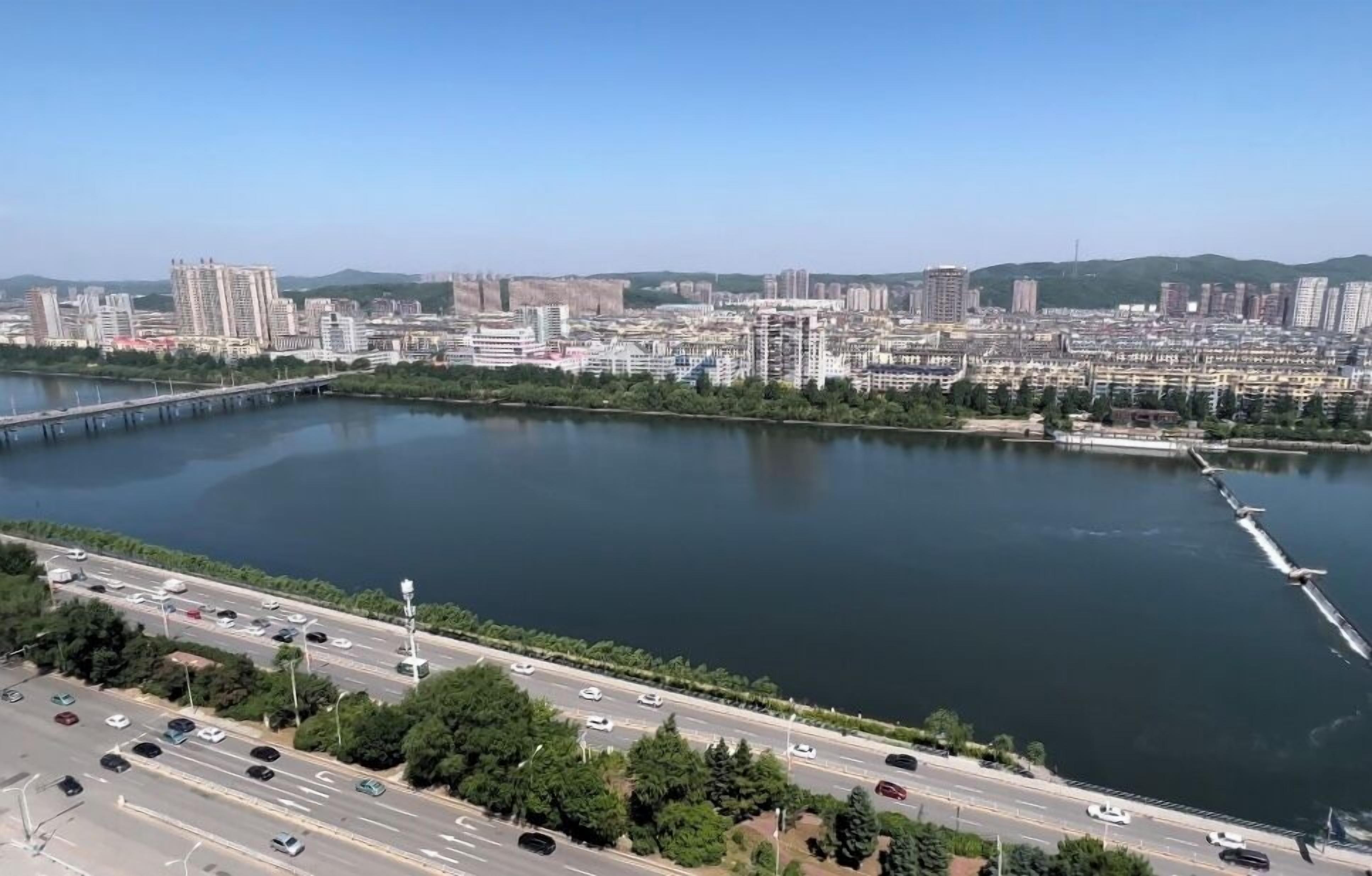 Un paisaje urbano con río, puente y autopista.