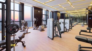 Un gimnasio moderno con diversos equipos de ejercicio, ventanas amplias y suelo de madera.