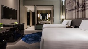 A modern hotel room with a large bed, a desk with a flat-screen TV, a bathroom with a large mirror, and a wall-mounted artwork. - Wanda Realm Wuhu (Wuhu)