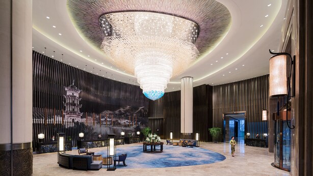 A spacious lobby with a large chandelier, a reception desk, and a seating area. - Wanda Realm Wuhu (Wuhu)